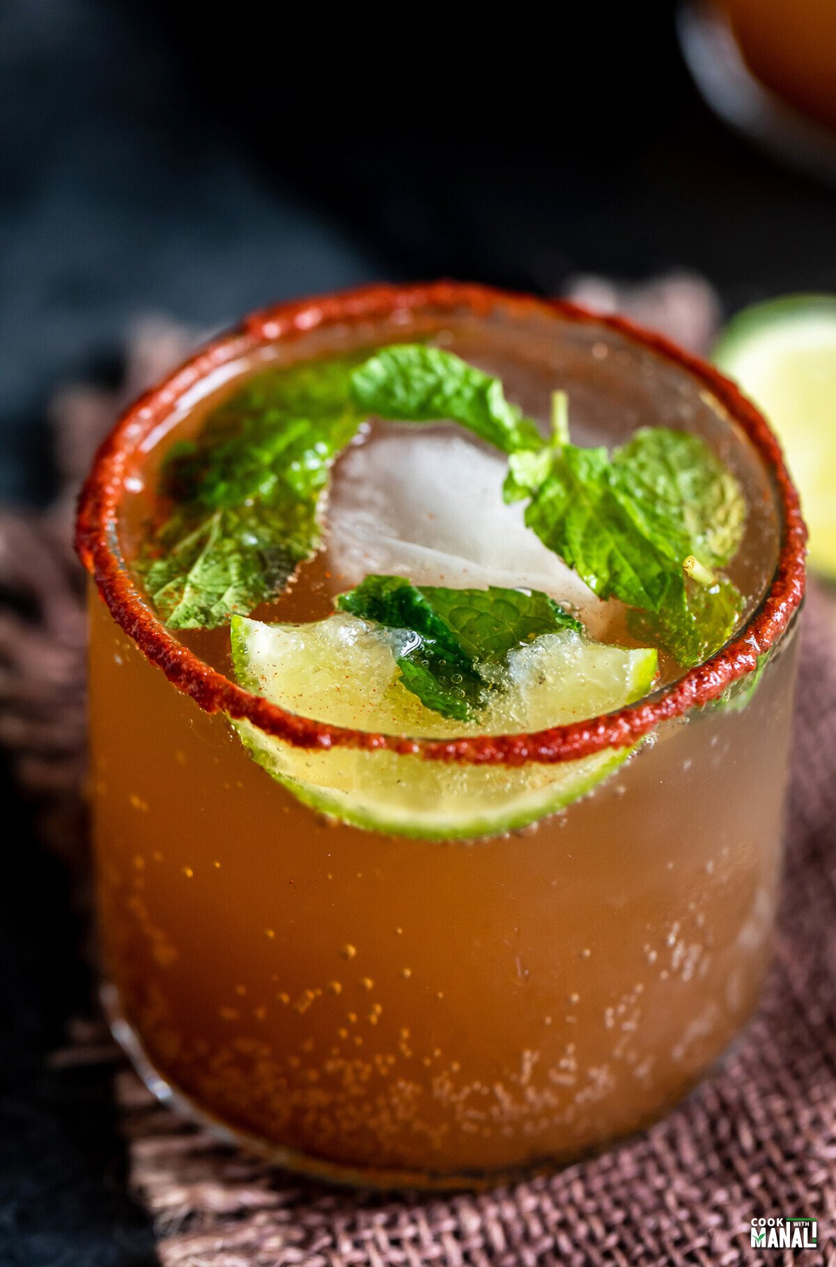 tamarind drink served in a glass topped with mint leaves and lemon wedges