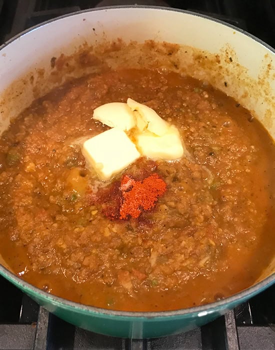 butter and red chili powder in pot of bhaji