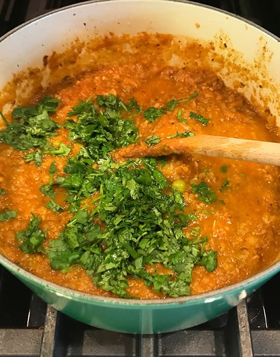 cilantro added to pot of bhaji