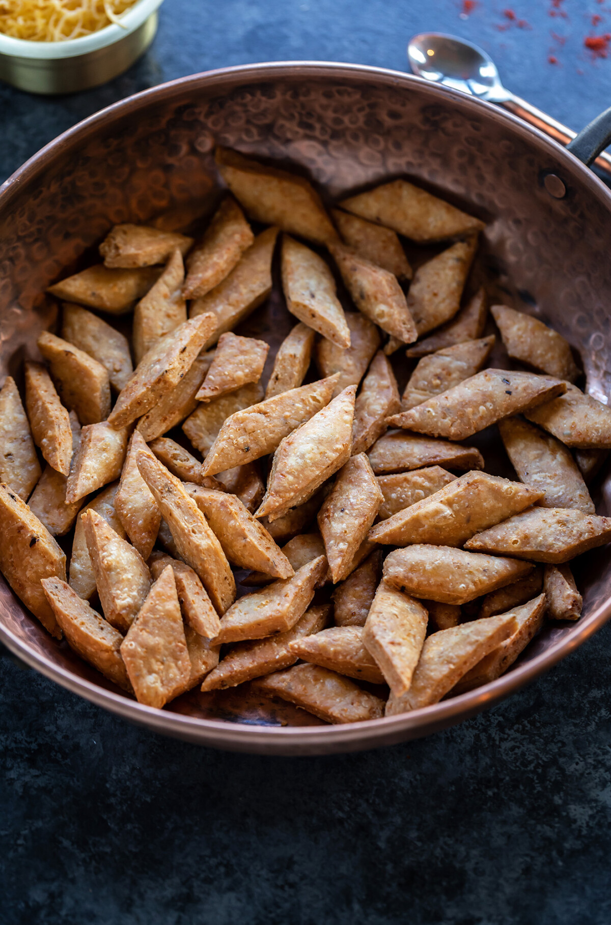 fried diamond shaped snack served in a copper round bowl