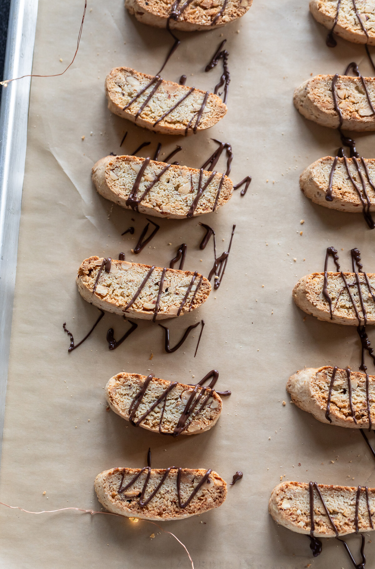biscotti drizzled with chocolate arranged on a baking sheet
