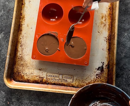 semi sphere silicone molds being filled with melted chocolate