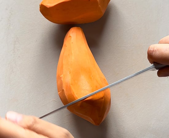 cutting peeled sweet potato with a knife