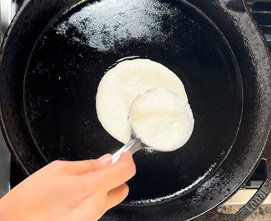 batter being spread on a cast iron pan