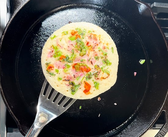 rava uttapam picked up with a spatula