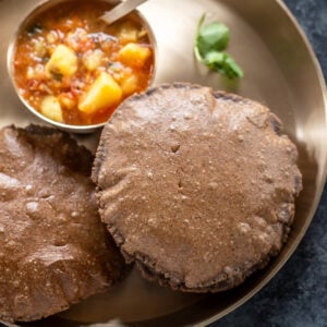 round puris served in a plate with aloo curry on the side