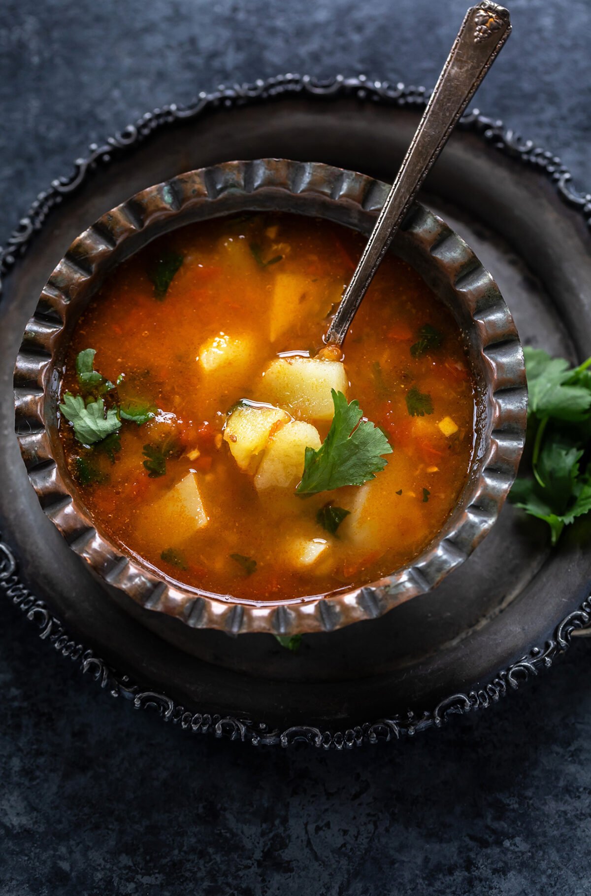 potato curry served in an antique bowl garnished with cilantro