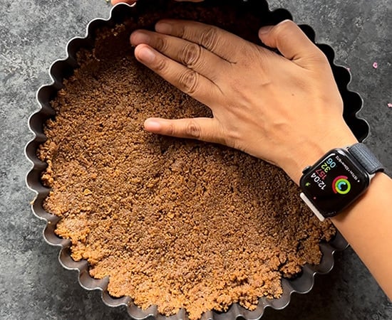 hand pressing the crust into a tart pan