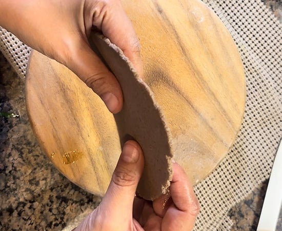 hands holding a puri to show it's thickness