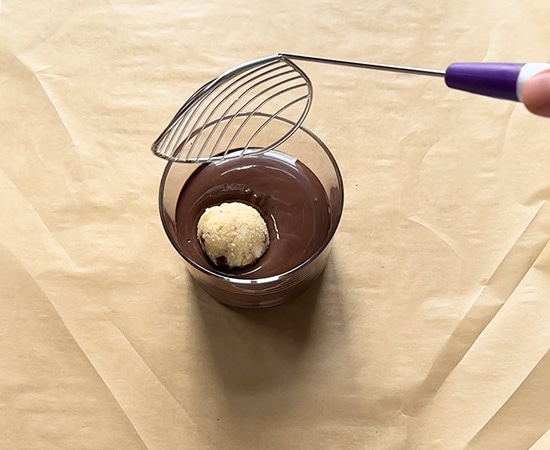 gujiya truffle being dipped in chocolate