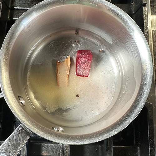 water in a pan with cinnamon stick and beetroot cube