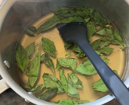 basil leaves with sugar and water in a pan