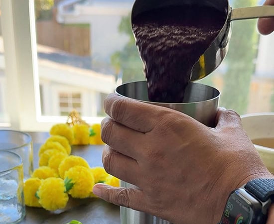 jamun pulp being added to a cocktail shaker