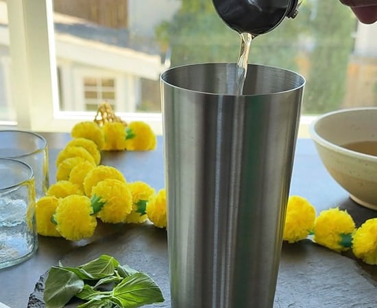 simple syrup being added to shaker with garland in the background