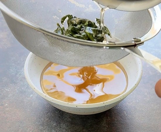 basil leaves being strained using a strainer