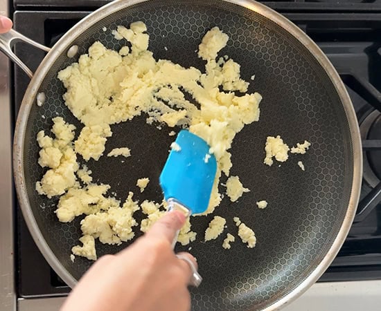 mawa being roasted in a a pan with a blue color spatula