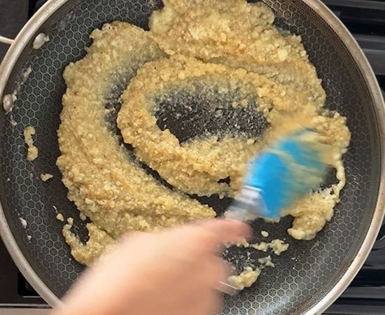 a blue color spatula mixing everything in a pan