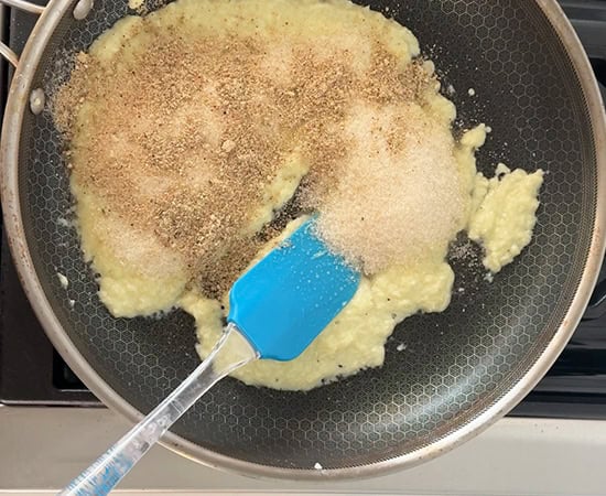 sugar and thandai powder being added to mawa in a pan