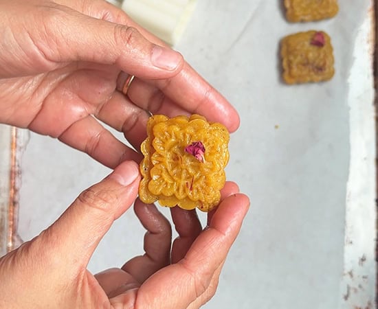 pair of hands holding a peda which is decorated with a rose petal