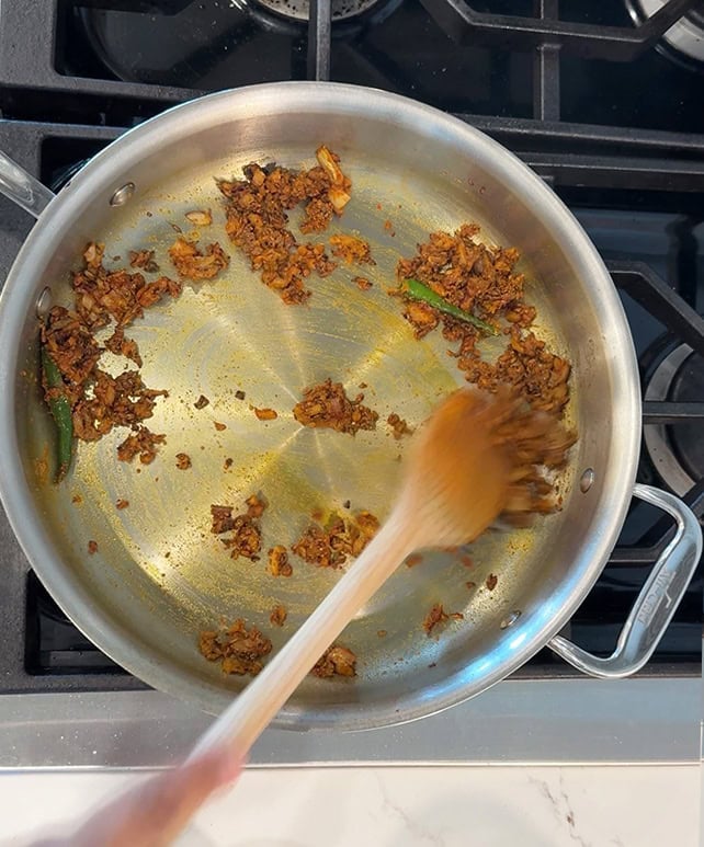 cooked spices with onions, chilies in a steel pan