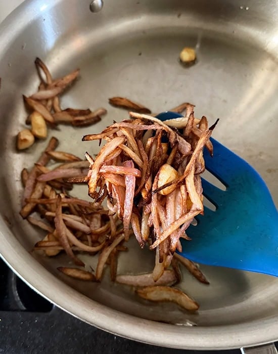 a spatula showing fried onion, garlic and ginger