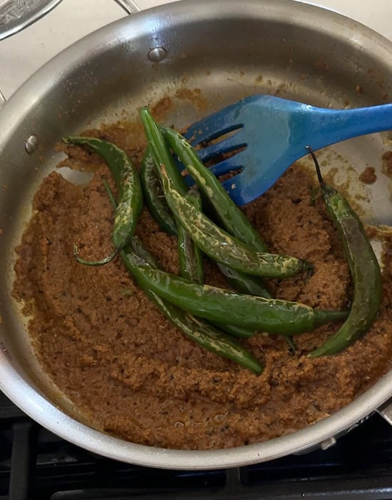 green chilies being added to masala in a pan