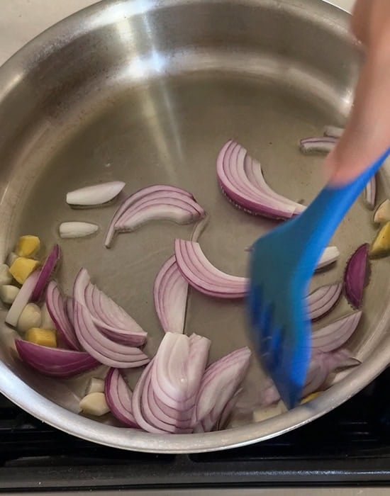 onions with garlic and ginger being fried in a steel pan