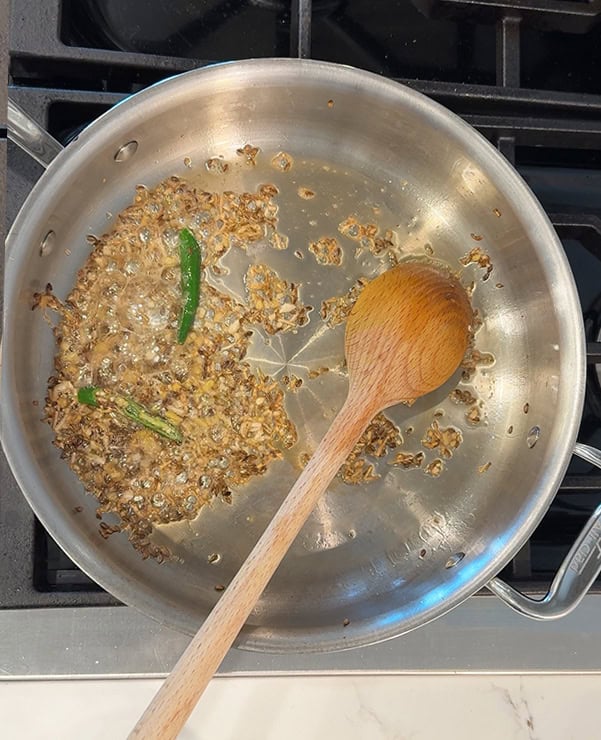 cooked ginger garlic with cumin seeds in a steel pan