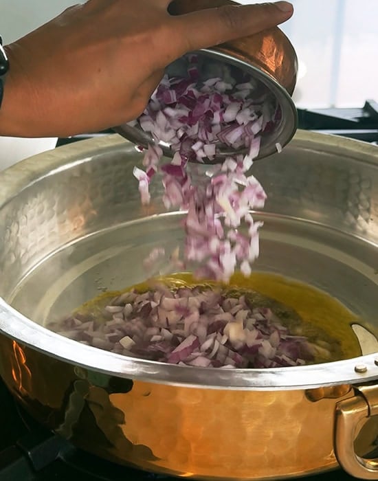 chopped onions being added to the pan