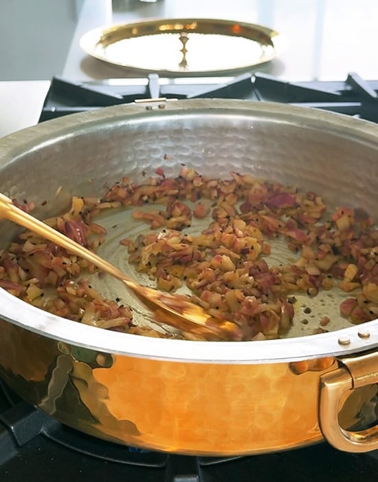onions being cooked in a pan