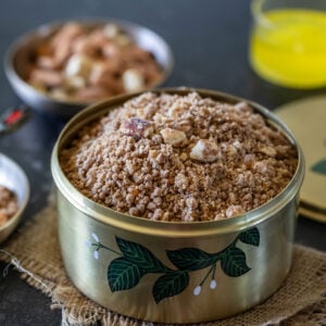 panjiri in a brass box garnished with nuts and a bowl of ghee placed in the background