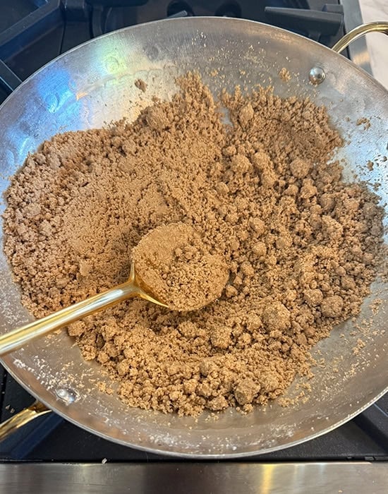 atta being roasted in a kadai with a spatula