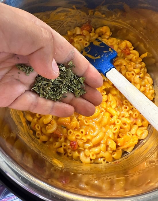 kasuri methi being added to a pot of pasta
