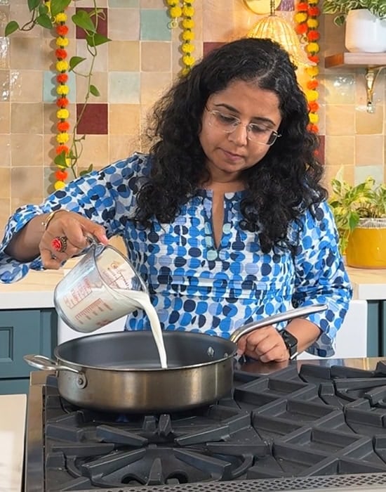 a woman adding milk to a pan