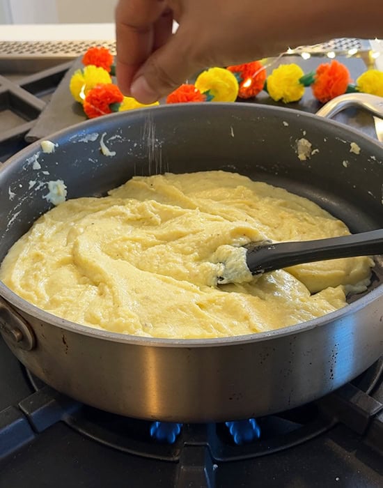 hand adding a pinch of something to a pan