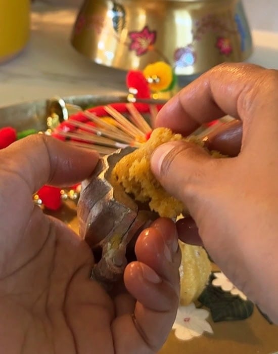 a hand pressing mawa inside a modak mold