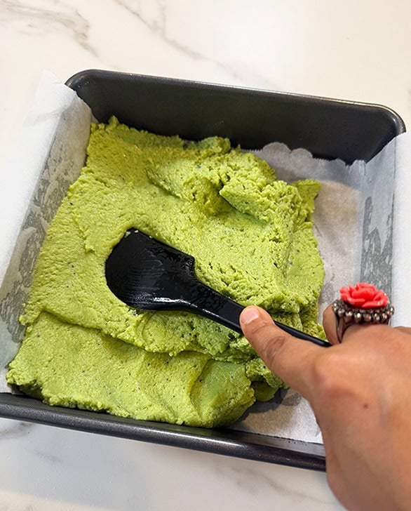 spatula pressing burfi mixture into a square pan