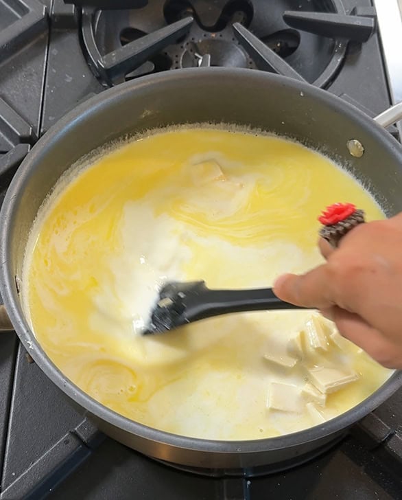 spatula stirring sugar and white chocolate with milk and butter