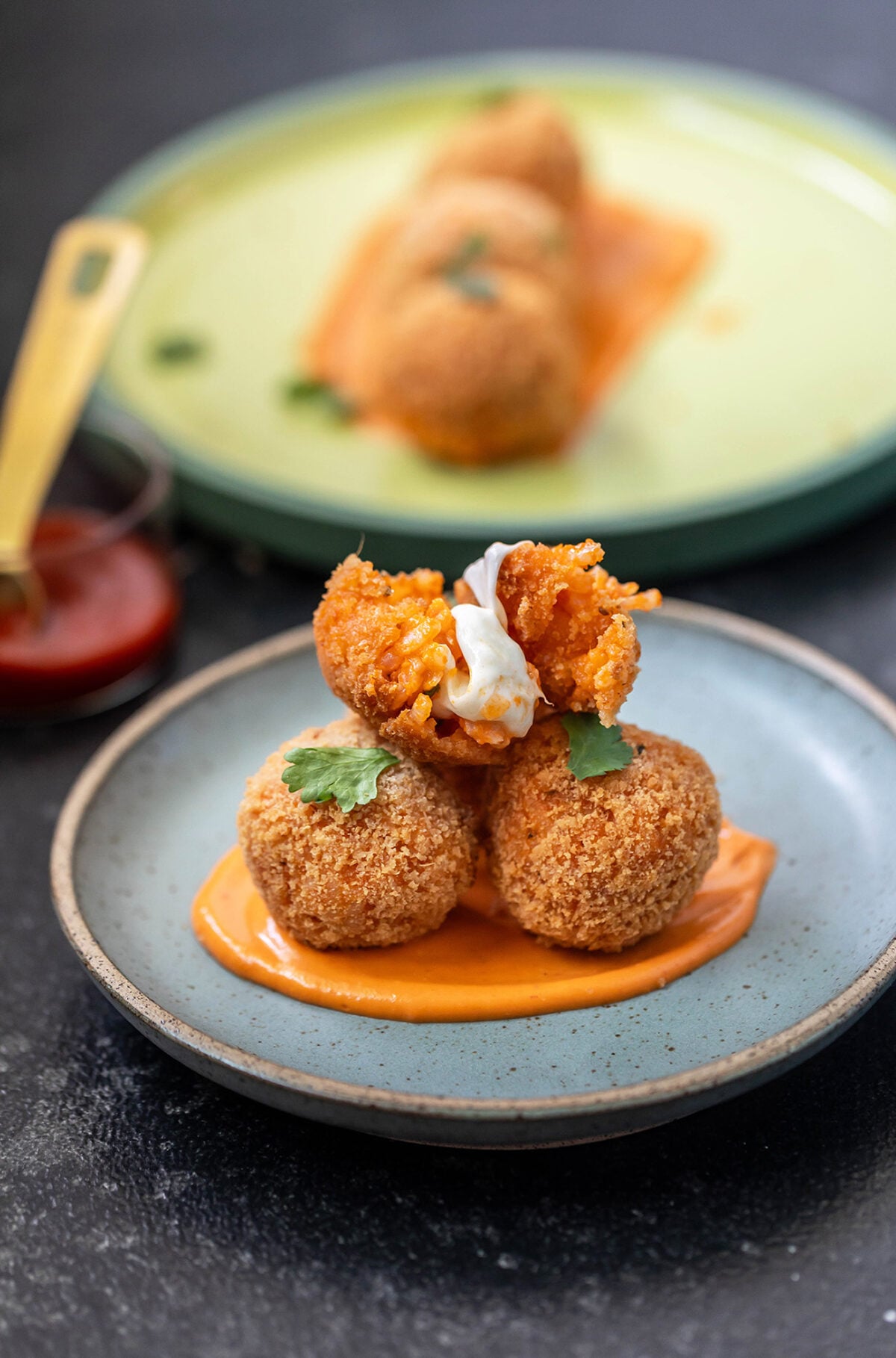 3 arancini with one broken in half to show the cheese pull