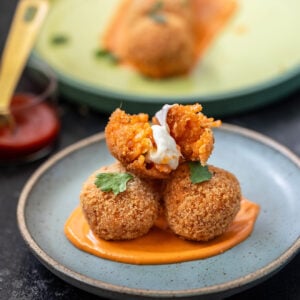 3 arancini with one broken in half to show the cheese pull