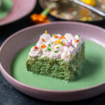 slice of cake in a pink color bowl with green color liquid poured around the cake