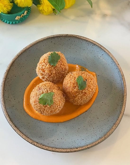 3 arancini in a bowl garnished with cilantro