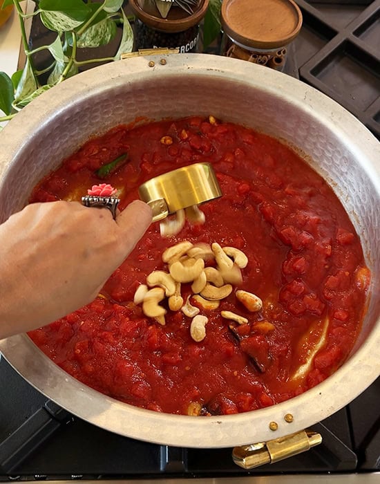 cashews with tomato sauce in a brass pab