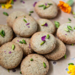 cookies garnished with rose petals and pistachios arranged on a baking sheet