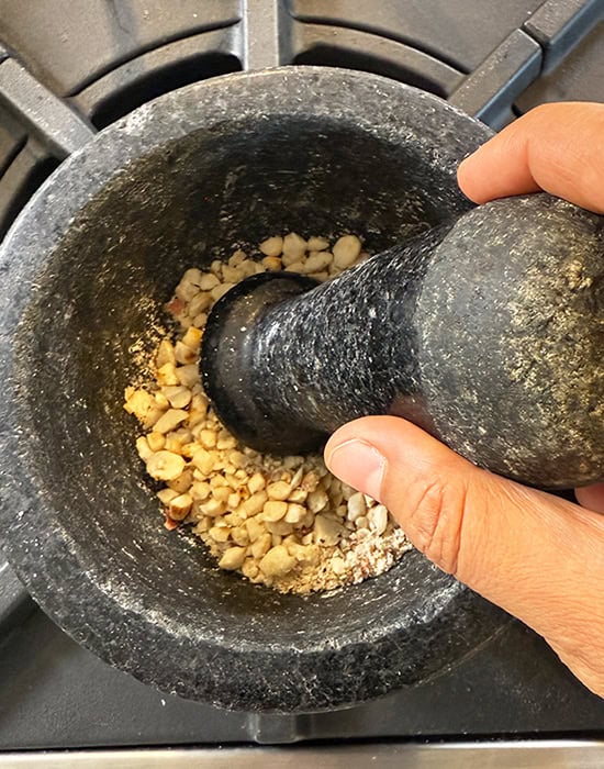peanuts being crushed in a mortar pestle