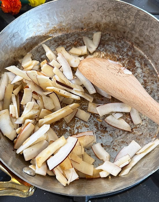 dried coconut being roasted in a pan