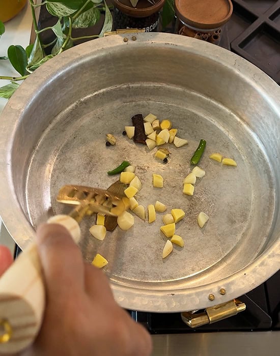 chopped ginger, garlic, whole spices in a brass pan