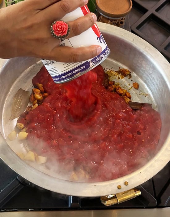 can of tomatoes being added to the pot