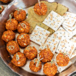 truffles with little skewers placed in a tray with crackers on the side