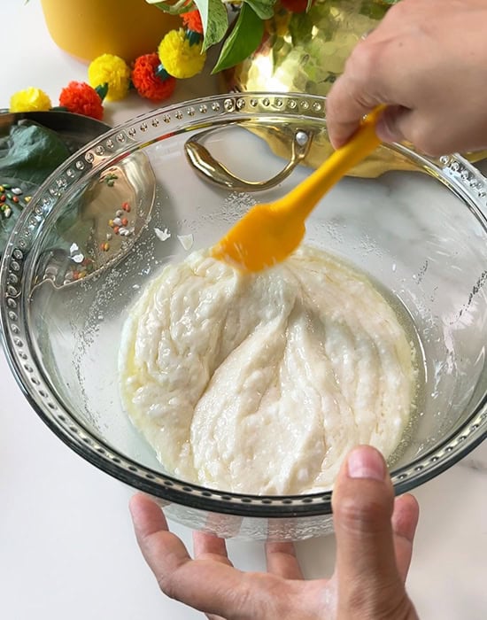 yogurt being mixed with oil and sugar in a bowl with a yellow spatula